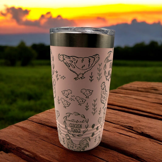 Pink tumbler with chicken design on a wooden surface with a sunset background